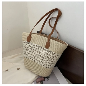 Close-up of straw tote bag showing beige hollow weave patterns and brown leather handles