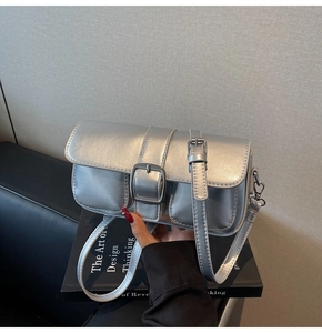 Detail of silver metallic crossbody bag with large decorative buckle and front pockets