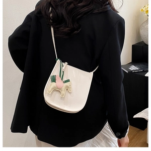 Detail of white lychee leather bucket bag with pink winged horse charm on model back