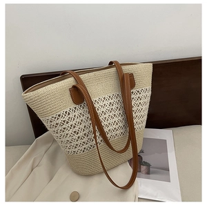 Detail of hollow woven straw tote bag featuring brown leather handles and stitching