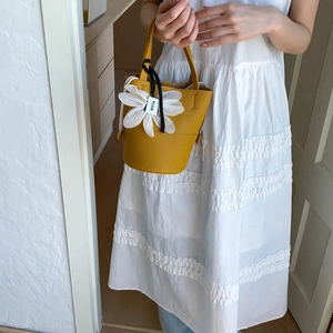 Detail of yellow bucket bag with lychee texture and 3D white flower charm detail