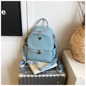 Détail d'un sac à dos bleu clair à texture litchi avec sangle sur valise argentée