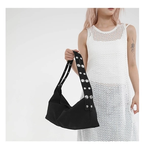 Detail of black canvas shoulder bag featuring punk style silver studs on wide strap