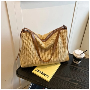 Détail du sac cabas en paille tissée avec anses en cuir marron et fermeture à glissière