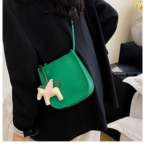 Detail of green litchi grain leather bucket bag with a decorative horse charm