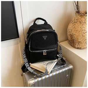 Détail d'un sac à dos en similicuir noir avec logo et bandoulière à motif géométrique