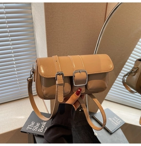 Detail of khaki leather crossbody bag with dual buckled pockets and silver hardware