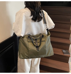 Rear view of a model carrying a large olive green nylon travel bag on wooden stairs