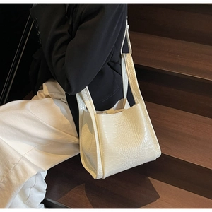 Detail of cream faux crocodile leather tote bag featuring a minimalist embossed texture