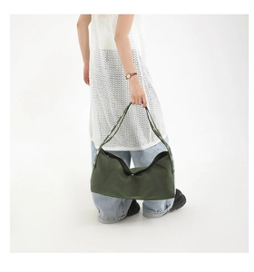 Detail of dark green canvas crescent bag showing thick matte fabric and silver metal eyelets