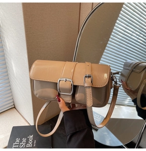 Detail view of stylish beige faux leather shoulder bag with silver square buckle and strap