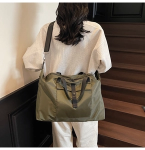Detail of army green travel bag with handles and adjustable strap worn by a model