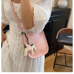 Pink lychee leather bucket bag detail with colorful winged horse charm accessory