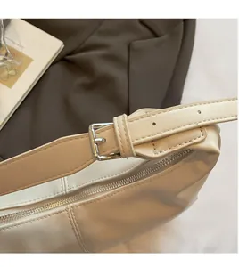 Detail of adjustable shoulder strap with silver buckle and smooth zipper on cream hobo bag