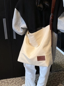 Large off-white canvas tote bag with brown leather straps shown on a model
