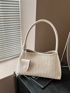 French style beige woven hobo shoulder bag with knotted handle on textured background