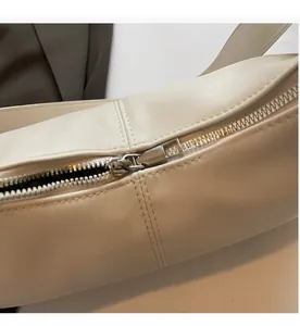 Detail shot of smooth silver metal zipper on cream white faux leather shoulder bag