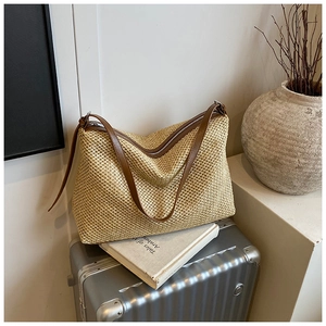 Détail du sac fourre-tout tissé avec poignées en cuir marron et fermeture éclair sur valise