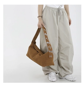 Detail of the brown suede shoulder bag showing metal rivets on wide strap and soft texture