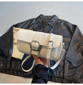 Macro detail of white patent leather shoulder bag with oversized silver metal buckle