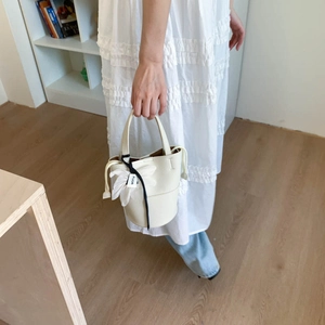 Minimalist white lychee leather bucket bag with elegant fabric flower and brand ribbon