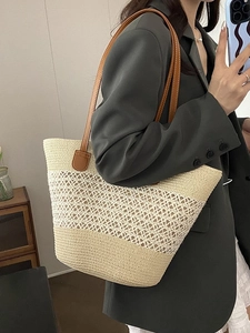 Minimalist straw tote bag with brown leather straps and hollow woven design shown on model