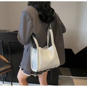 Detail view of a white crocodile embossed bucket bag styled on a female model