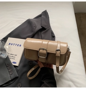 Close-up of beige patent leather shoulder bag with glossy finish and silver buckles