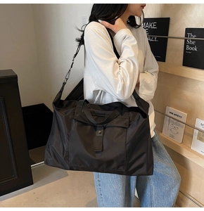 Large black travel bag detail showing nylon texture and adjustable shoulder strap buckle