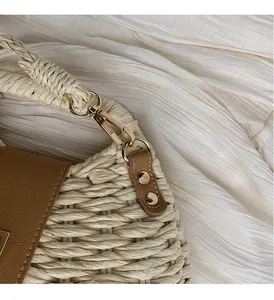 Detail of woven straw texture with brown leather flap and gold hardware on crossbody bag
