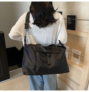 Detail of black nylon travel bag with adjustable strap and front buckle pocket