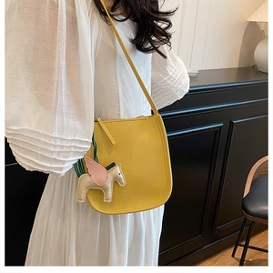 Detail of yellow lychee leather bucket bag featuring a colorful pegasus horse charm