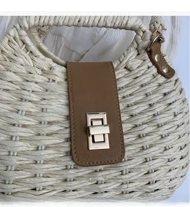 Detail of premium golden twist lock on stylish woven straw bag with brown leather trim