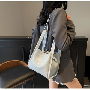 Detailed view of crocodile pattern tote bag shown over the shoulder with thin strap