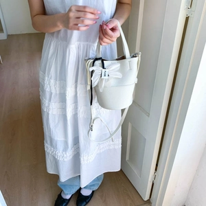 Detailed shot of white lychee leather bucket bag with decorative floral charm detail