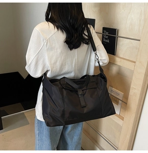 Large black travel bag shown on shoulder model, featuring waterproof fabric and spacious design