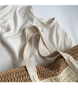 Close-up of contrast woven straw tote bag and textured beige cotton linen shirt