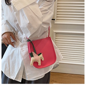 Detail view of pink lychee leather bucket bag with a colorful pegasus charm on a model