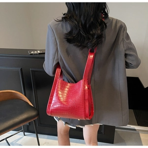 Detailed back view of a woman wearing the red crocodile pattern bucket bag with grey suit