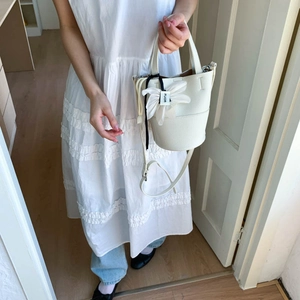 Close-up of white bucket bag with pebble leather texture and floral charm detail