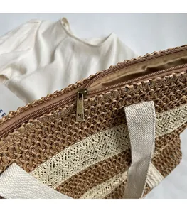 Close-up of smooth metal zipper and striped straw weave detail on a large beach tote