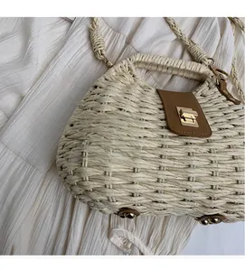 Detailed view of woven straw bag featuring brown leather flap and golden twist lock