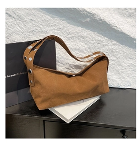Detail of a brown suede hobo bag featuring large silver metal eyelets and soft texture