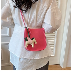 Detail view of pink leather shoulder bag featuring a decorative Pegasus horse charm