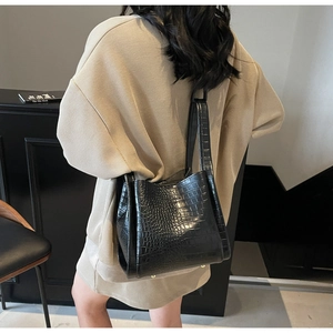 Rear view of model wearing a black crocodile pattern crossbody bucket tote bag