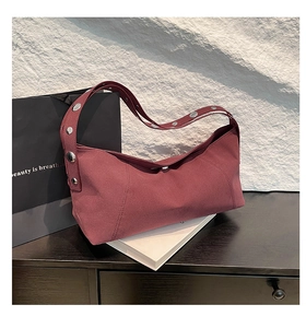 Close-up of retro burgundy hobo bag with large silver metal rivets on the shoulder strap