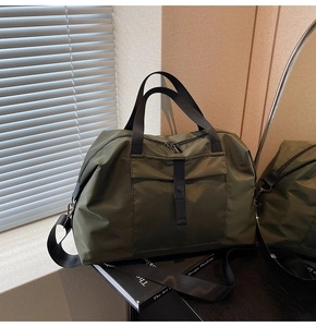 Detail of army green travel duffel bag with black straps and waterproof nylon texture