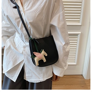 Detail of black pebbled leather bucket bag with a pink and beige Pegasus horse charm