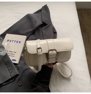 Detail of cream white rectangular shoulder bag featuring vintage double buckle flap pockets