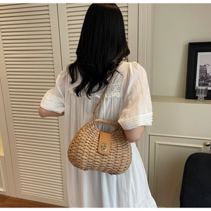 Detail of woven straw half-moon crossbody bag with metal buckle on white summer dress